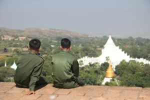 Photo of Myanmar soldiers sitting looking at the horizon.