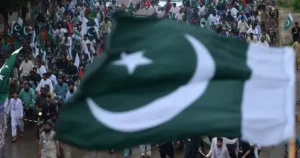 Pakistan flag with a group of people behind.