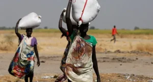 Sudanese people carrying food aid over their heads.